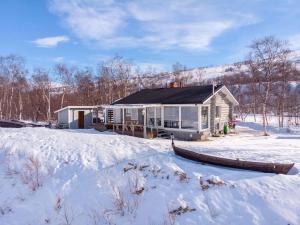 NuorgamBeautiful riverside cottage with sauna的雪中的房子,有雪覆盖的院子