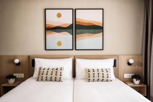 埃尔哥茨拉Strand Suites by NEU Collective的一间卧室配有两张床,墙上有两幅画作