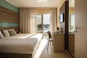 埃尔哥茨拉115 The Strand Hotel by NEU Collective的酒店客房设有一张床、一张书桌和窗户。