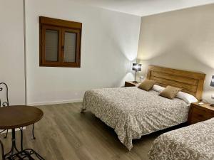 莱里达Casa Rural Namasté con SPA的一间卧室设有两张床、一张桌子和一个窗口