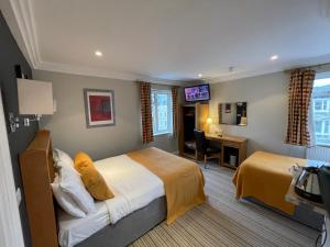 泰晤士河畔里士满Shandon Hotel的配有床和书桌的酒店客房