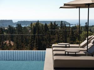 瓦西里科斯Alexandra SeaView Luxurious Villa, By ThinkVilla的一个带2把躺椅和遮阳伞的游泳池