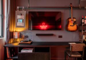 曼彻斯特BrewDog DogHouse Manchester的一张桌子、一台电视和墙上的吉他