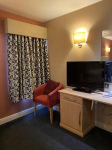 The Windmill Inn的酒店客房配有书桌、电视和椅子