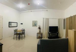 TunghaanDeluxe studio unit at Modena Town Sq的客厅配有桌椅和电视。