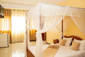 图利亚拉Amazone Hotel Tulear的卧室配有带白色窗帘的天蓬床