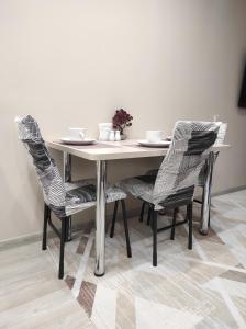 阿拉木图Уютная квартира-студия ЖК Lotus Terrace的餐桌,配有两把椅子和一张白色的桌子