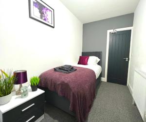 格里姆斯比Chantry Suites的一间卧室配有一张带紫色毯子的床