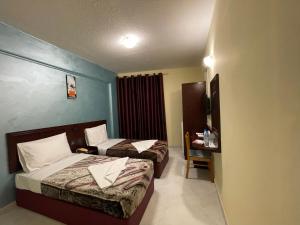 迪拜MOUNT SINA HOTEL By AURA的酒店客房配有两张床和一张书桌