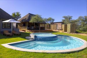奥马鲁鲁TimBila Camp Namibia的一个带遮阳伞的庭院内的游泳池