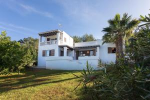 伊斯费古耶拉尔海滩Casa en Ibiza con vistas increíbles en Es Figueral的院子里有棕榈树的白色房子