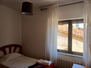 绍塞列Casa rural Las Peñas的一间卧室配有床和白色窗帘的窗户
