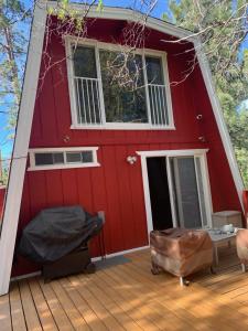 大熊湖Maison Solange-Red Barn Farmhouse Style- Moonridge的红色的房子,配有带一张床和椅子的甲板