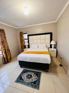 姆巴巴内GoldenWays Apartments的一间卧室配有一张大床和地毯。