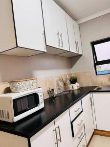 姆巴巴内GoldenWays Apartments的厨房配有白色橱柜和台面上的微波炉