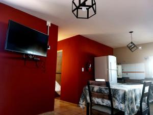卡皮亚德尔德尔蒙特Jazmin del Cielo的一间设有红色墙壁、电视和桌子的房间