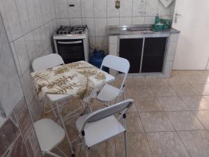 瓜拉廷格塔Meu Cantinho E的厨房配有白色的椅子、桌子和炉灶。