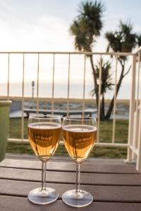 西塞德Inn of the Four Winds Seaside Oceanfront的坐在桌子上一边欣赏海滩美景,一边享用两杯葡萄酒