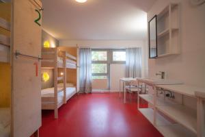 柏林BIG MAMA Berlin的一间设有双层床的客房,铺有红色地板