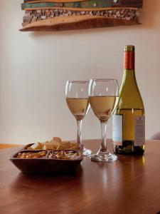 QuilquicoRefugio Pullao的一张桌子,上面放着两杯葡萄酒和一盘奶酪