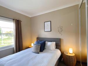 格莱诺基Stunning Hobart 3-bed home- close to shopping centers的一间卧室配有一张带两盏灯的床和一扇窗户。