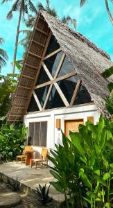 锡基霍尔Bermuda Triangle Bungalows的茅草屋顶和桌椅的房子