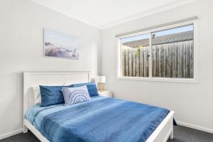 卡尔斯The Seas at Phillip Island的白色卧室设有蓝色的床和窗户