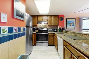 大洋城Sea Watch 1110的厨房配有木制橱柜和不锈钢冰箱。
