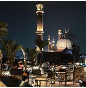新德里爱玩夏希酒店 的一群人晚上坐在屋顶的桌子上