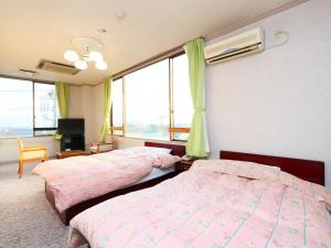 SanmuSeaside Hotel Kujukuri的一间卧室设有两张床、一台电视和窗户。