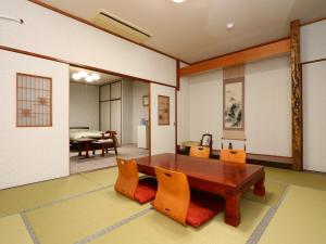 SanmuSeaside Hotel Kujukuri的一间带木桌和椅子的用餐室