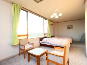 SanmuSeaside Hotel Kujukuri的一间卧室配有一张床、两把椅子和一个窗户