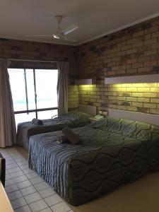 温顿Boulder Opal Motor Inn的一间卧室设有两张床和砖墙