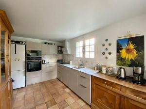 贝诺代Maison de famille près de la mer的厨房配有白色家电,墙上挂着向日葵画