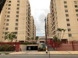 瓜鲁雅Apartamento Enseada的两栋高大的建筑,在街道旁设有红色的围栏