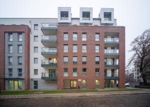 格但斯克Maya's Flats & Resorts 49 - 3 rooms flat in Szafarnia Gdansk的白色建筑前的红砖建筑