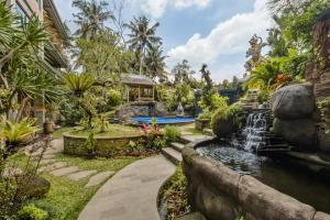 乌布Gynandha Ubud Cottage的一个带瀑布和游泳池的花园