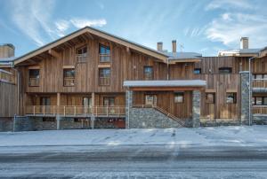 蒙特瓦勒赞Appartement Panorama, résidence Les Alpages的一座大木结构建筑,地面上积雪