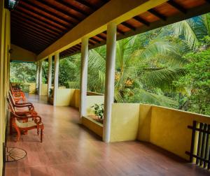 KudaweBlue Magpie Lodge Sinharaja的一个带椅子和棕榈树的房子的门廊