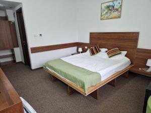 拉姆尼库沃尔恰Pensiunea Carpe Diem的一间卧室配有一张大床和木制床头板