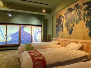 大阪Osaka Ukiyoe Ryokan的一间卧室设有两张床,墙上挂着一幅画