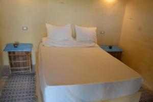 Tunisمنتجع تونس فاير- Tunis Fire Resort的一张大白色的床,位于带两张桌子的房间
