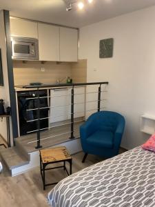 圣特罗佩Apartment Eden Park的一间卧室配有一张床和一张蓝色椅子,还设有一间厨房