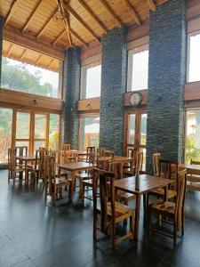 康格拉Osho Himalayas Wellness Resort的餐厅设有木桌、椅子和时钟