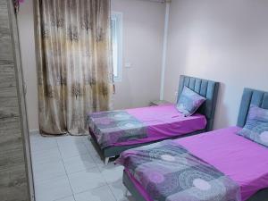 Ḩammām al GhazzāzFamily house的配有粉红色和紫色床单的客房内的两张床