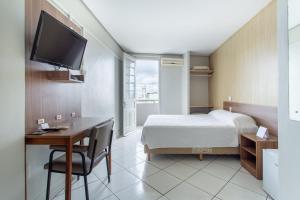 圣玛丽亚Hotel Dom Rafael Express的酒店客房配有一张床、一张书桌和一台电视。