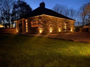 CoxhoeDunromin Cottage, Hot Tub & Garden的夜晚在院子里有灯的石头房子