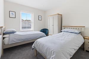 布里克瑟姆Bolton Plaice, Brixham的一间卧室设有两张床和窗户。