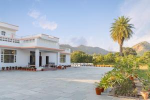 乌代浦Jass Bagh Home stay Udaipur I swimming pool I wedding I 87oo2o5865的一座棕榈树和山峰背景的建筑