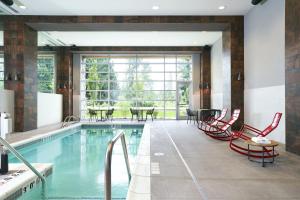 雷德蒙德Archer Hotel Seattle/Redmond的一个带红色椅子和桌子的游泳池